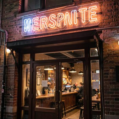 a neon sign glowing above a bar entrance