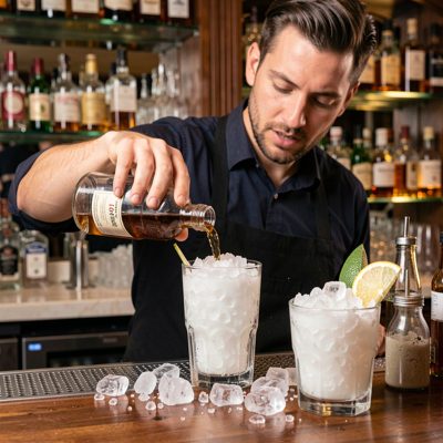 a barman filling a cocktail with crushed ice