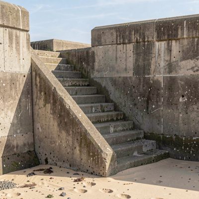 a sea wall with steps down to the sand