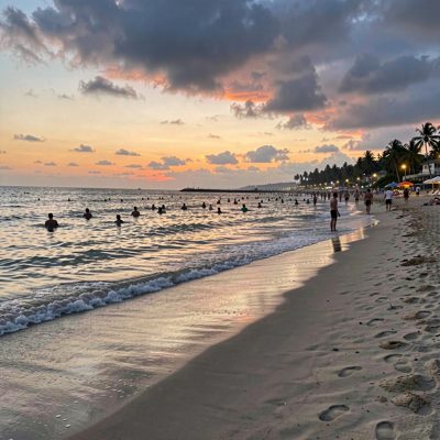 a beach at dusk with the last swimmers