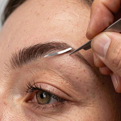an eyebrow being shaped with tweezers