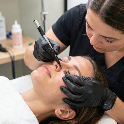 a lash technician working with a client's eyes closed