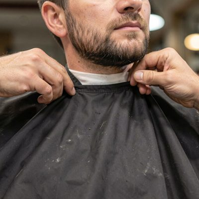 a barber's cape being fastened at the neck