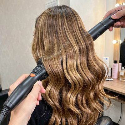 a curling wand creating a wave in long hair
