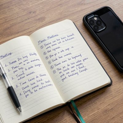 an open notebook with handwritten meeting notes and a phone