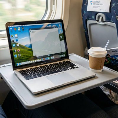 a laptop and takeaway coffee on a train tray table