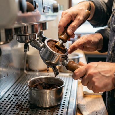 a barista tamping coffee grounds into a portafilter