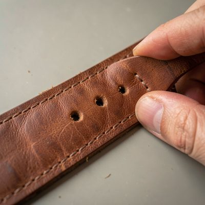 a leather punch making holes in a strap