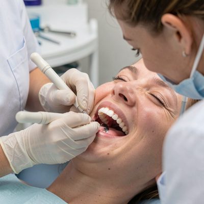 a hygienist scaling a patient's teeth