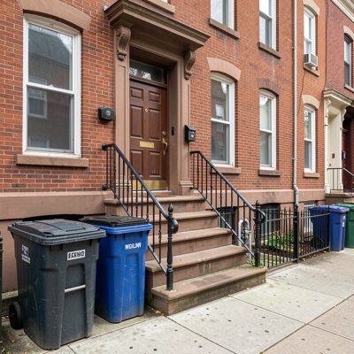 a walk up apartment with a stoop and bins