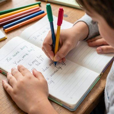 a child's hands writing in an exercise book
