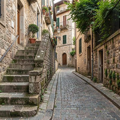 a cobbled hill street with steps at one side