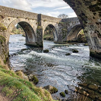 a stone bridge with arches over a river