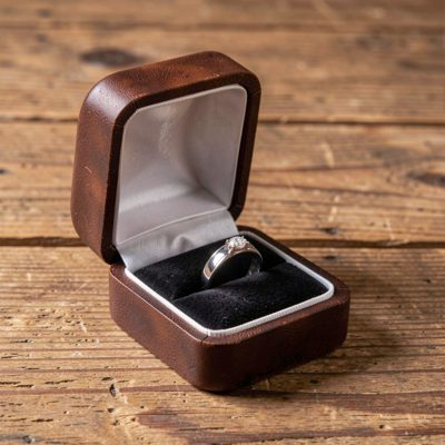 a wedding ring box open on a wooden surface
