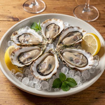 a plate of oysters on crushed ice with lemon