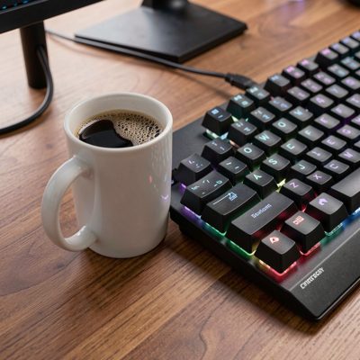 a coffee mug beside a gaming keyboard