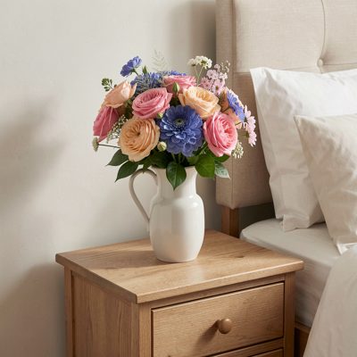a bedside table with fresh flowers in a jug