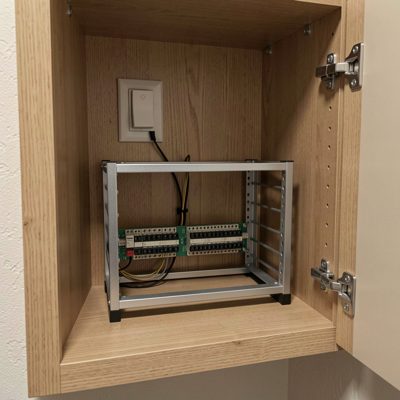 a small rack in a hallway cupboard with a switch and patch panel