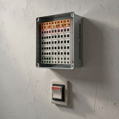 a wall mounted patch panel above a small switch