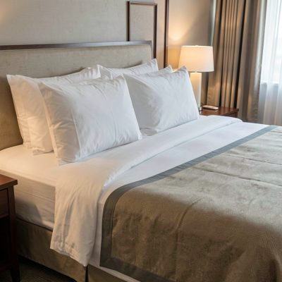 a hotel bed with pillows plumped and a runner across