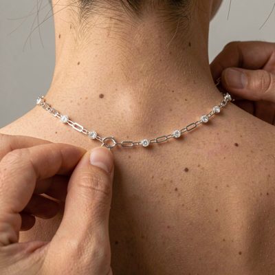 a necklace being clasped at the back of a neck