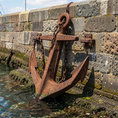 a rusting anchor on a harbour wall