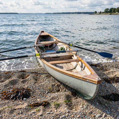 a rowing dinghy pulled up on shingle