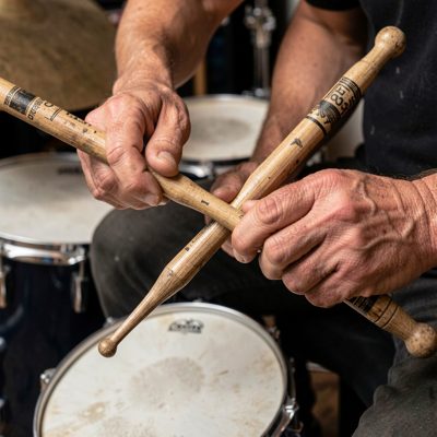 a drummer's hands holding worn sticks