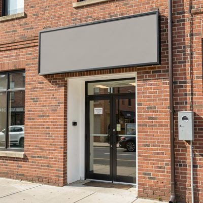 a brick commercial building entrance with a blank sign panel, blank empty sign board, no text, no lettering, no logo