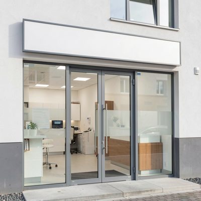 a modern clinic entrance with an empty sign panel over the doors, blank empty sign board, no text, no lettering, no logo