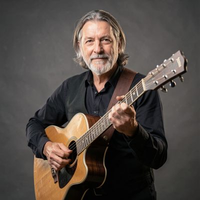 a musician holding a guitar and looking to camera