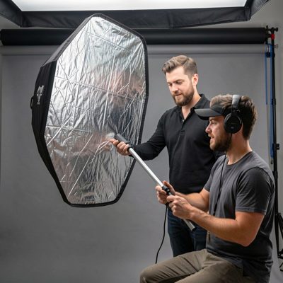 a photo shoot with an assistant holding a reflector