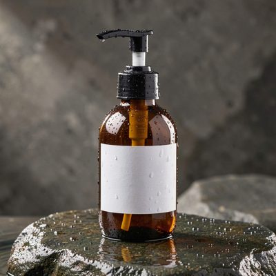 a pump bottle on wet stone with water droplets and a blank white label