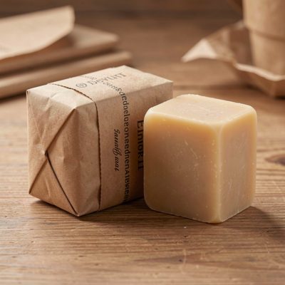 a soap bar unwrapped beside its paper sleeve