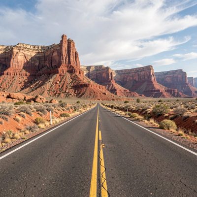 a red rock mesa beyond a straight road