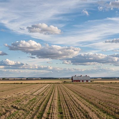 a wide sky over flat farmland with a barn