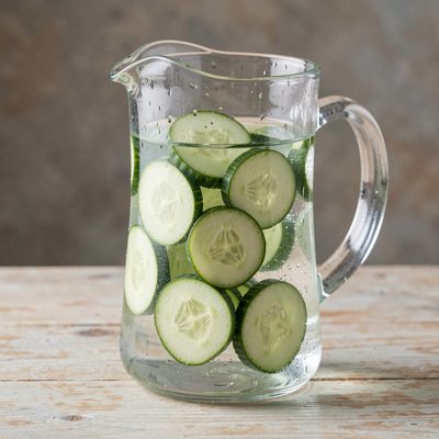 a chilled water jug with cucumber slices