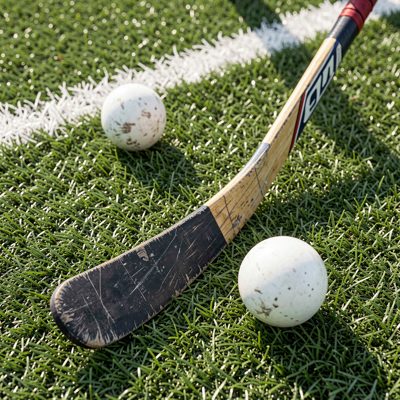 a hockey stick and ball on artificial turf