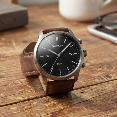 a round faced smartwatch resting on a wooden desk