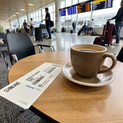 a boarding pass and coffee on a departure lounge table