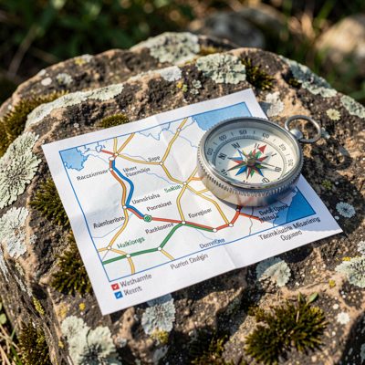 a walking route map and compass on a rock