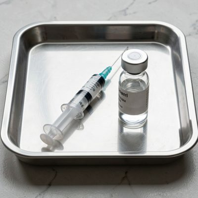 a syringe and vial on a stainless tray