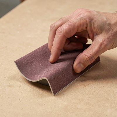 a hand sanding block on a curved edge