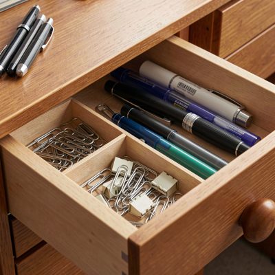 a desk drawer with pens and paper clips
