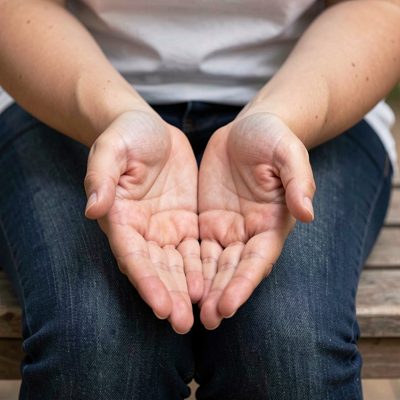 hands resting palms up on crossed knees