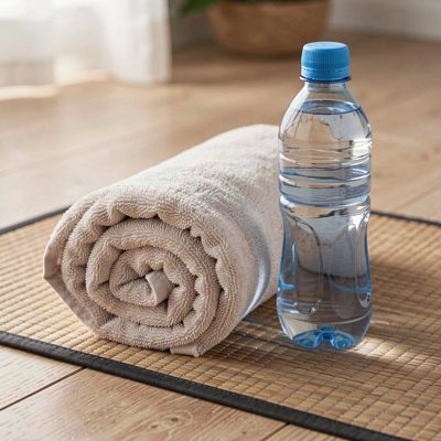 a rolled towel and water bottle beside a mat